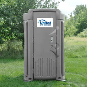 Portable toilet located on a grassy area with trees and shrubbery in the background.