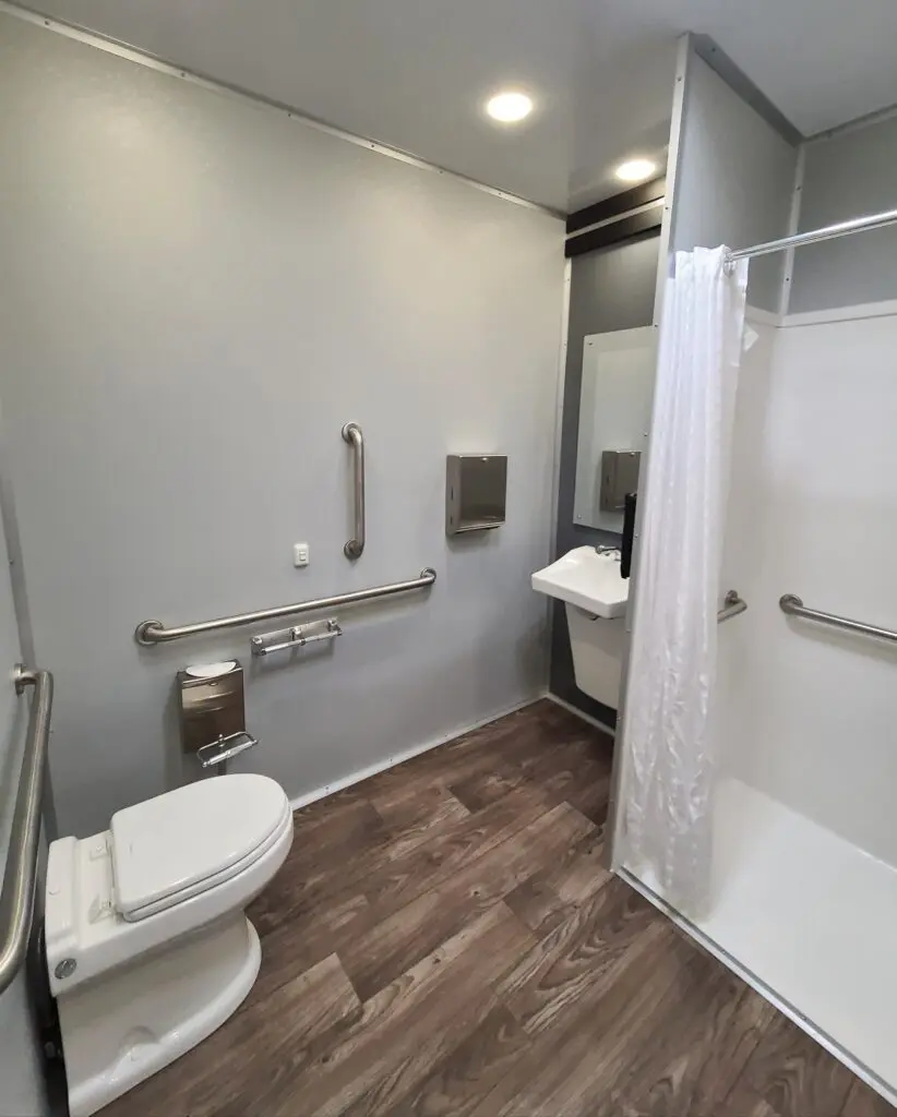 ada bathroom shower trailer interior view of the toilet, sink and shower. all areas have hand rails for safety